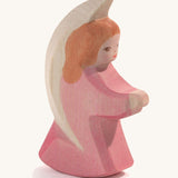 A wooden pink Ostheimer little angel figure on a cream background.