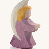 A wooden purple Ostheimer little angel figure on a cream background.