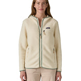 A woman wearing the Patagonia Retro Pile Hoody available at Babipur. A women's fleece style jacket in a light cream colour with green trim. Features a full length zip, 2 side pockets, a chest pocket and a logo patch stitched on the left chest.