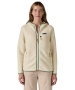 A woman wearing the Patagonia Retro Pile Hoody available at Babipur. A women's fleece style jacket in a light cream colour with green trim. Features a full length zip, 2 side pockets, a chest pocket and a logo patch stitched on the left chest.
