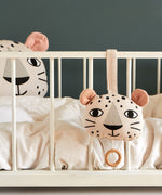 Roommate Musical Baby Mobile - Leopard and Roommate Leopard cushion on a baby cot bed