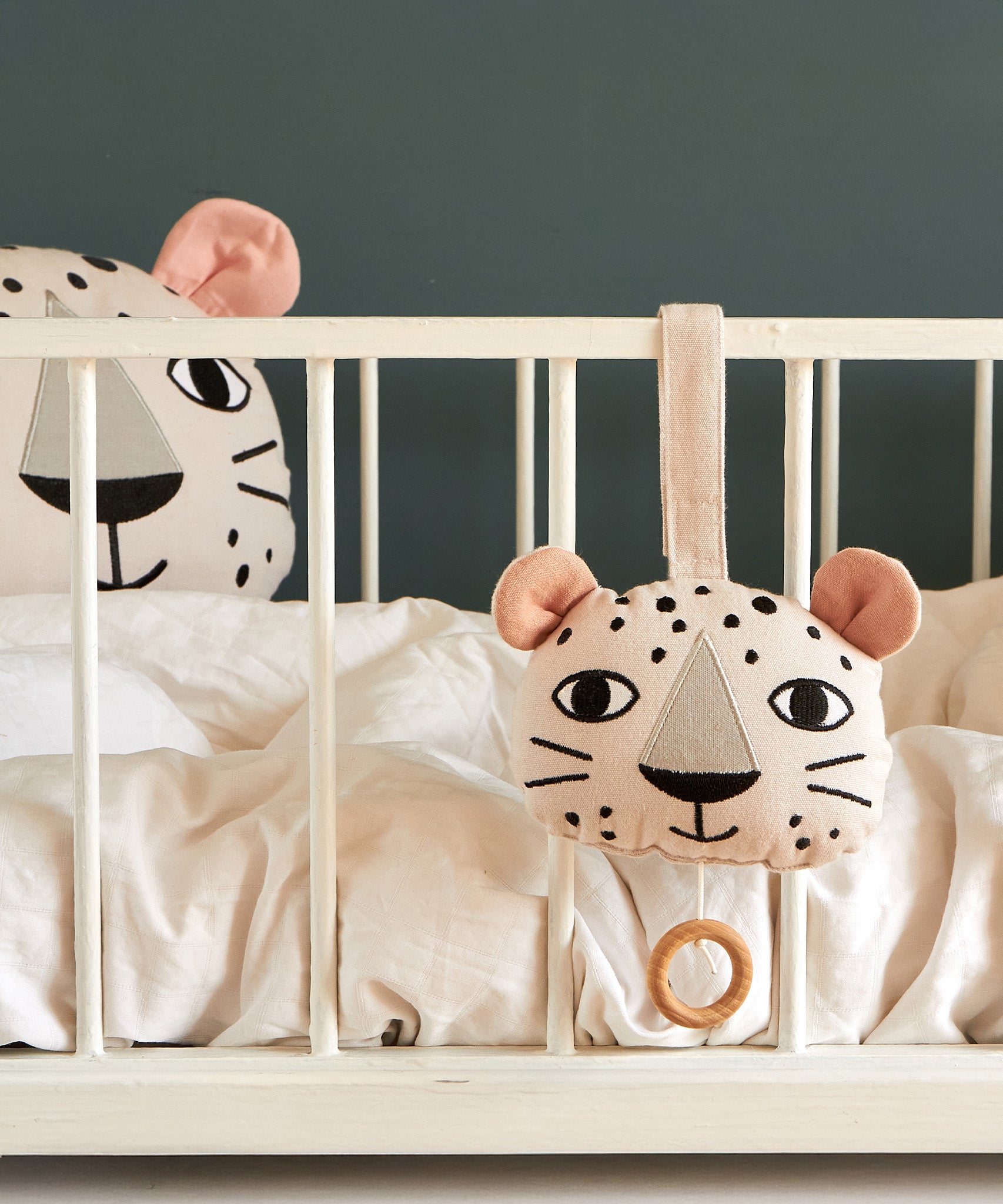 Roommate Musical Baby Mobile - Leopard and Roommate Leopard cushion on a baby cot bed