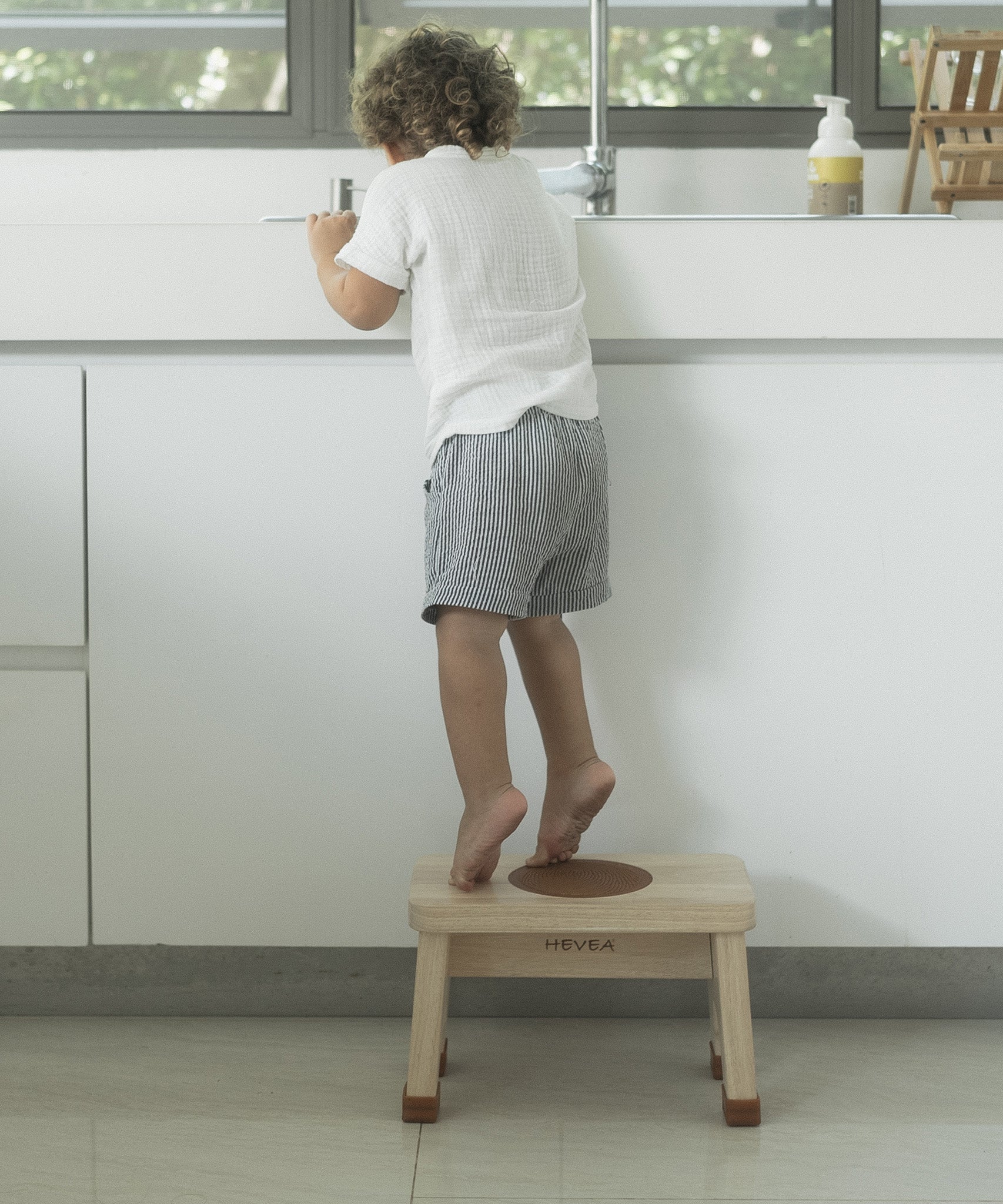 Child in stood on a Hevea Rubberwood Step Stool reaching into a sink.