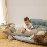 A child sitting on top the Senger giant grey soft and cuddly whale toy next to a large whale for scale. This soft toy is available at Babipur.