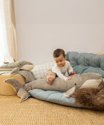 A child sitting on top the Senger giant grey soft and cuddly whale toy next to a large whale for scale. This soft toy is available at Babipur.