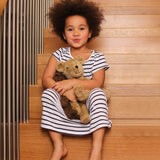 A child sat on wodden stairs, holding a Senger Large Floppy Beige Bear and small brown bear