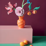 Studio roof small Dutch masters inspired bouquet decoration available at Babipur displayed in a orange vase standing on a pink platform