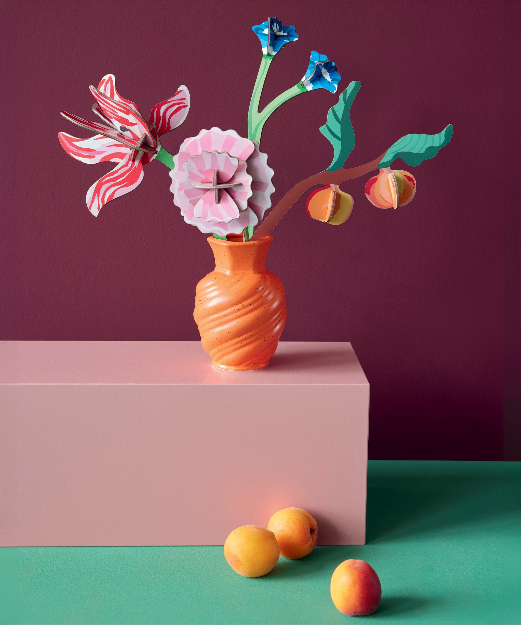 Studio roof small Dutch masters inspired bouquet decoration available at Babipur displayed in a orange vase standing on a pink platform