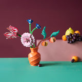 Studio roof small Dutch masters inspired bouquet decoration available at Babipur displayed in a orange vase next to a bunch of fruit