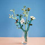 Studio roof small Van Gough inspired bouquet with almond blossom decoration available at Babipur displayed in a glass against a blue background.
