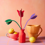 Studio Roof cardboard bouquet in tulip love colour way available at Babipur. A DIY kit made from cardboard displayed in a homemade red paper mache vase next to a watering jug and fruit bowl