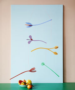 A Studio Roof cardboard Cordelia floral art mobile hanging over a table. This multicoloured floral DIY cardboard set is available at Babipur.