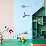 A Studio Roof cardboard Cordelia floral art mobile hanging over a table. This multicoloured floral DIY cardboard set hangs by thin string and  available at Babipur.