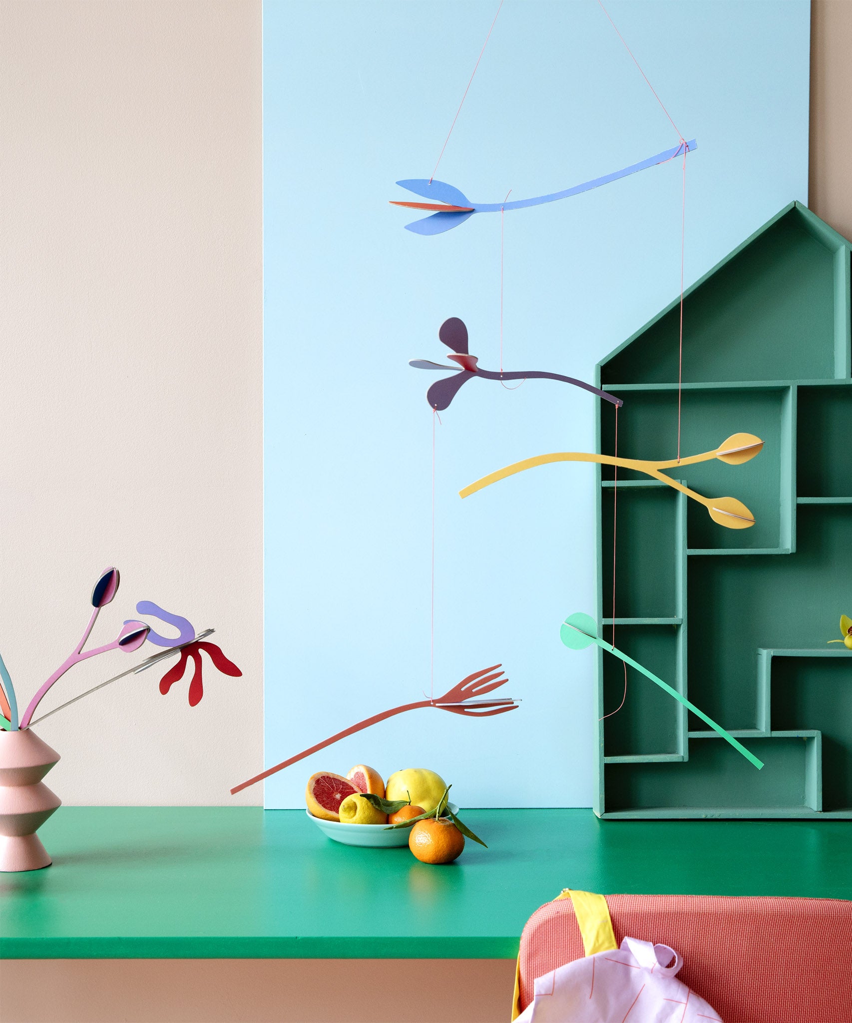 A Studio Roof cardboard Cordelia floral art mobile hanging over a table. This multicoloured floral DIY cardboard set hangs by thin string and  available at Babipur.