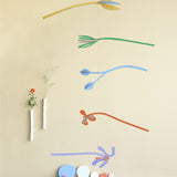 A Studio Roof cardboard Ophelia floral art mobile hanging over a table. This multicoloured floral DIY cardboard set is available at Babipur.