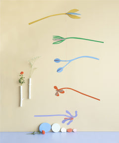 A Studio Roof cardboard Ophelia floral art mobile hanging over a table. This multicoloured floral DIY cardboard set is available at Babipur.