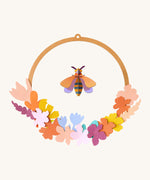 Studio Roof wreath meadow with bee available at Babipur. A DIY kit made from cardboard in a floral wreath design with a bee hanging from the loop.