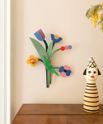 Daisy belle wall decoration available at Babipur hanging on a wall above above a wooden drawer next to a giant wooden peg doll. A Studio roof collaboration with artist Zoe Miller.