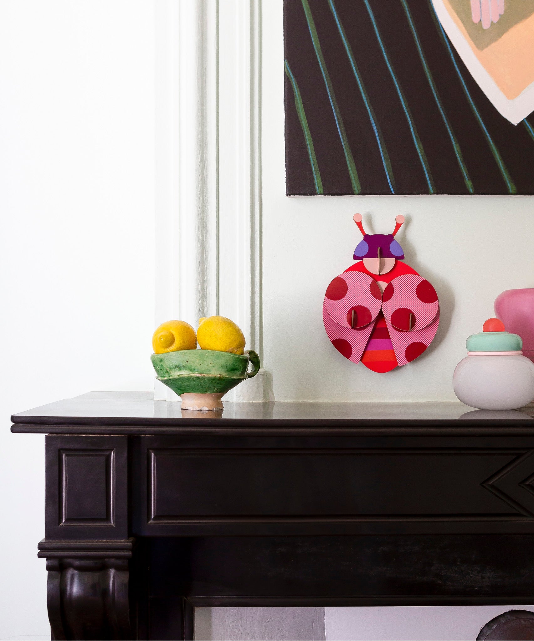 Dotted lady wall decoration available at Babipur hanging on a wall above a mantlepiece next to a bowl of lemons and pots. A Studio roof collaboration with artist Zoe Miller.