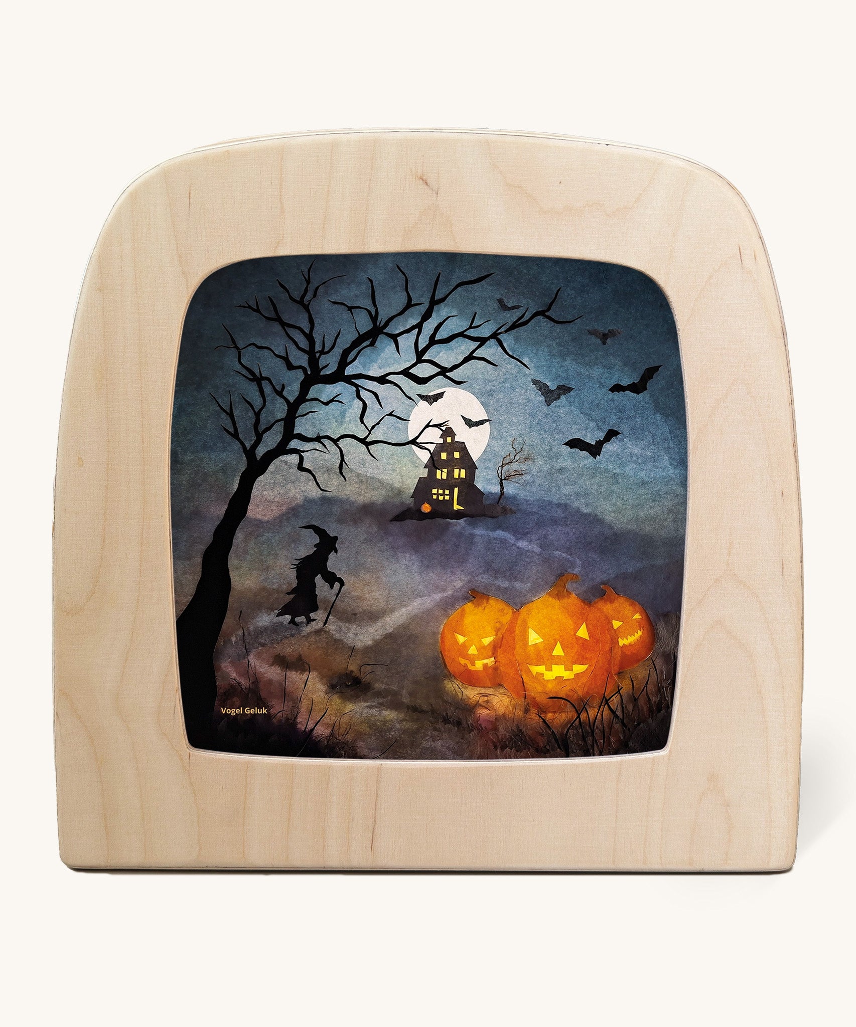 A Toverlux silhouette inside a wooden  lamp. This silhouette is a spooky scene with a witch walking towards a house with bats flying and scary pumpkins on the floor . This layered paper style silhouette is by artist Vogel Geluk and available at Babipur.