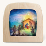 A Toverlux silhouette inside a wooden  lamp. This silhouette is a nativity inspired scene with Mary and Joseph standing over baby Jesus in a stable. This layered paper style silhouette is by artist Vogel Geluk and available at Babipur.