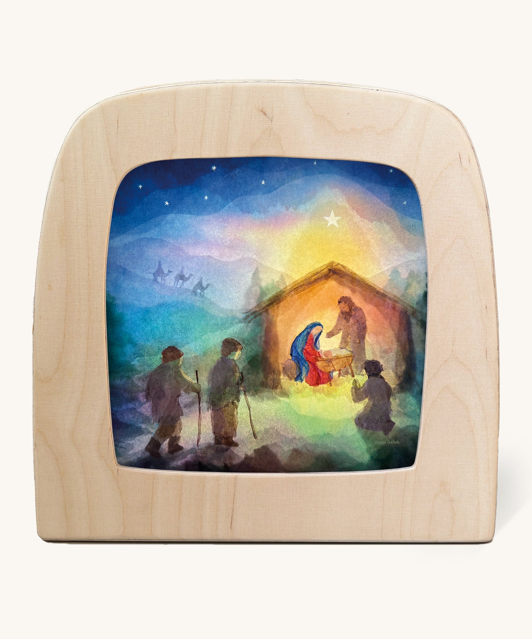 A Toverlux silhouette inside a wooden  lamp. This silhouette is a nativity inspired scene with Mary and Joseph standing over baby Jesus in a stable. This layered paper style silhouette is by artist Vogel Geluk and available at Babipur.