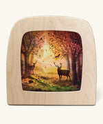 A Toverlux silhouette inside a wooden  lamp. This silhouette has 2 stag deers in an Autumn woodland scene. This layered paper style silhouette is by artist Vogel Geluk and available at Babipur.