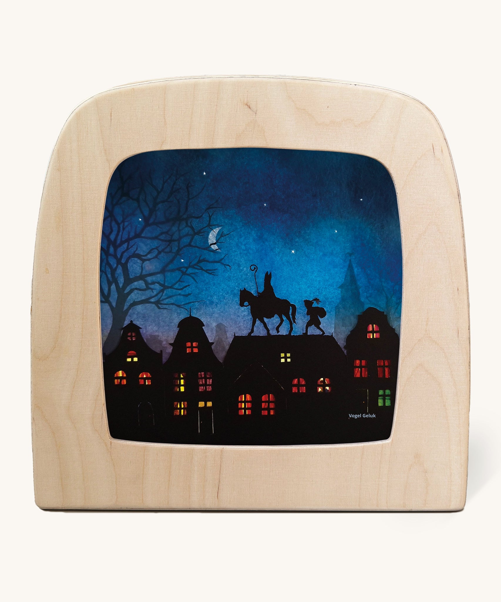 A Toverlux silhouette inside a wooden  lamp. This silhouette has St Nicholas on a horse on top of a roof undr a moonlit sky with an elf following. This layered paper style silhouette is by artist Vogel Geluk and available at Babipur