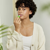 A woman applying the Weleda skin food lip balm on her lips. This balm is available at Babipur.