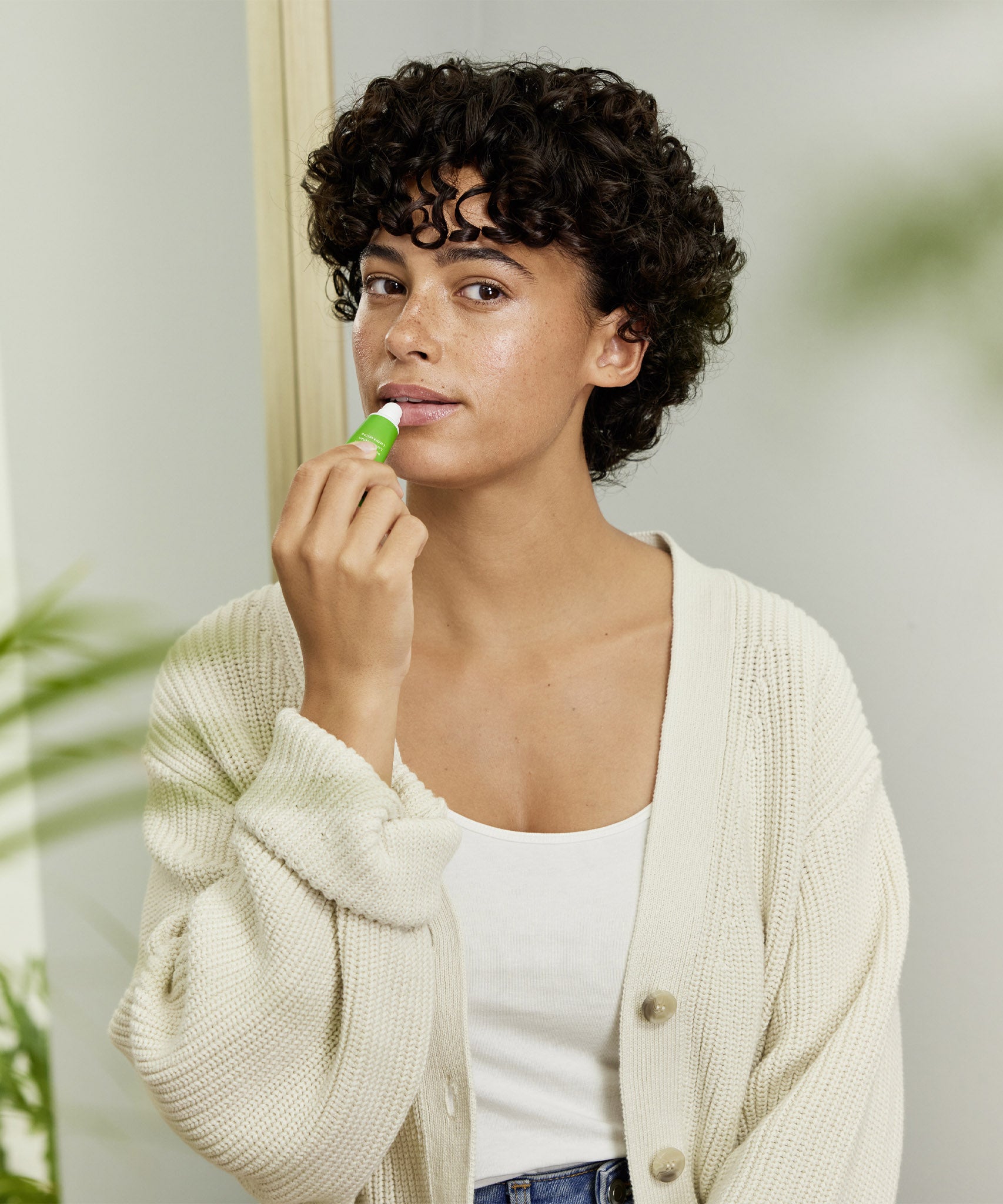 A woman applying the Weleda skin food lip balm on her lips. This balm is available at Babipur.
