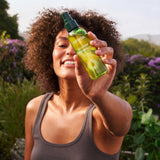 A woman holding the the Weleda skin food ultra light dry oil. This bottle is available at Babipur.