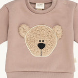 A close up of the Wooly Organic embroidered sweater in pale blush pink /savannah available at Babipur showing the cute fluffy teddy bear embroidery on the front and popper fastener detail