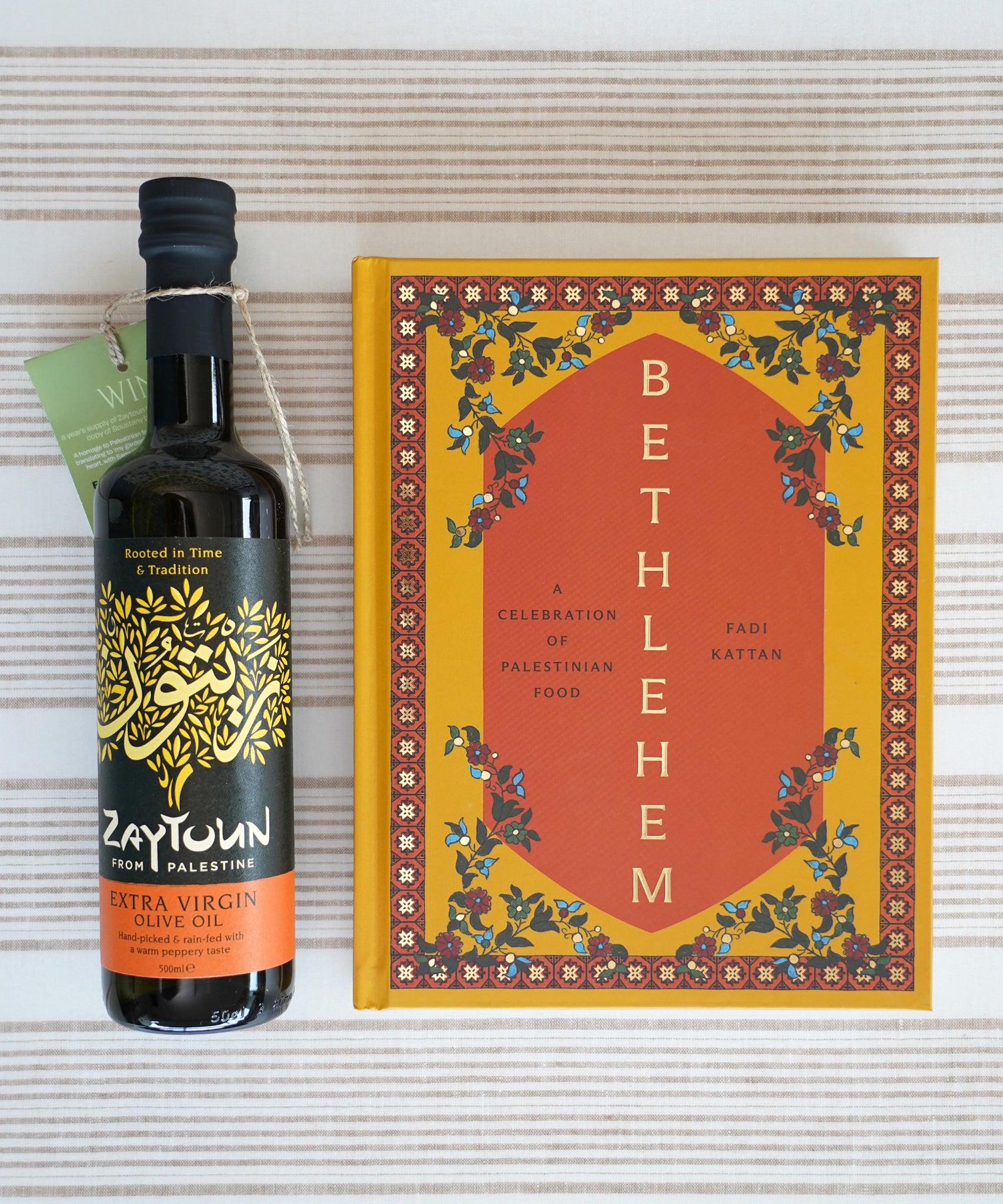 Filled with authentic Palestinian recipes, the Zaytoun Bethlehem Cookbook by Fasi Kattan is a true celebration of the region’s food next to a bottle of Fairtrade Olive Oil — find it at Babipur.