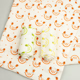 A Slice Of Green set of 3 rainbow organic cotton muslin cloths showing the orange design cloth laid flat with the lime and lemon cloth on top.