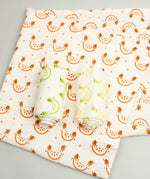 A Slice Of Green set of 3 rainbow organic cotton muslin cloths showing the orange design cloth laid flat with the lime and lemon cloth on top.