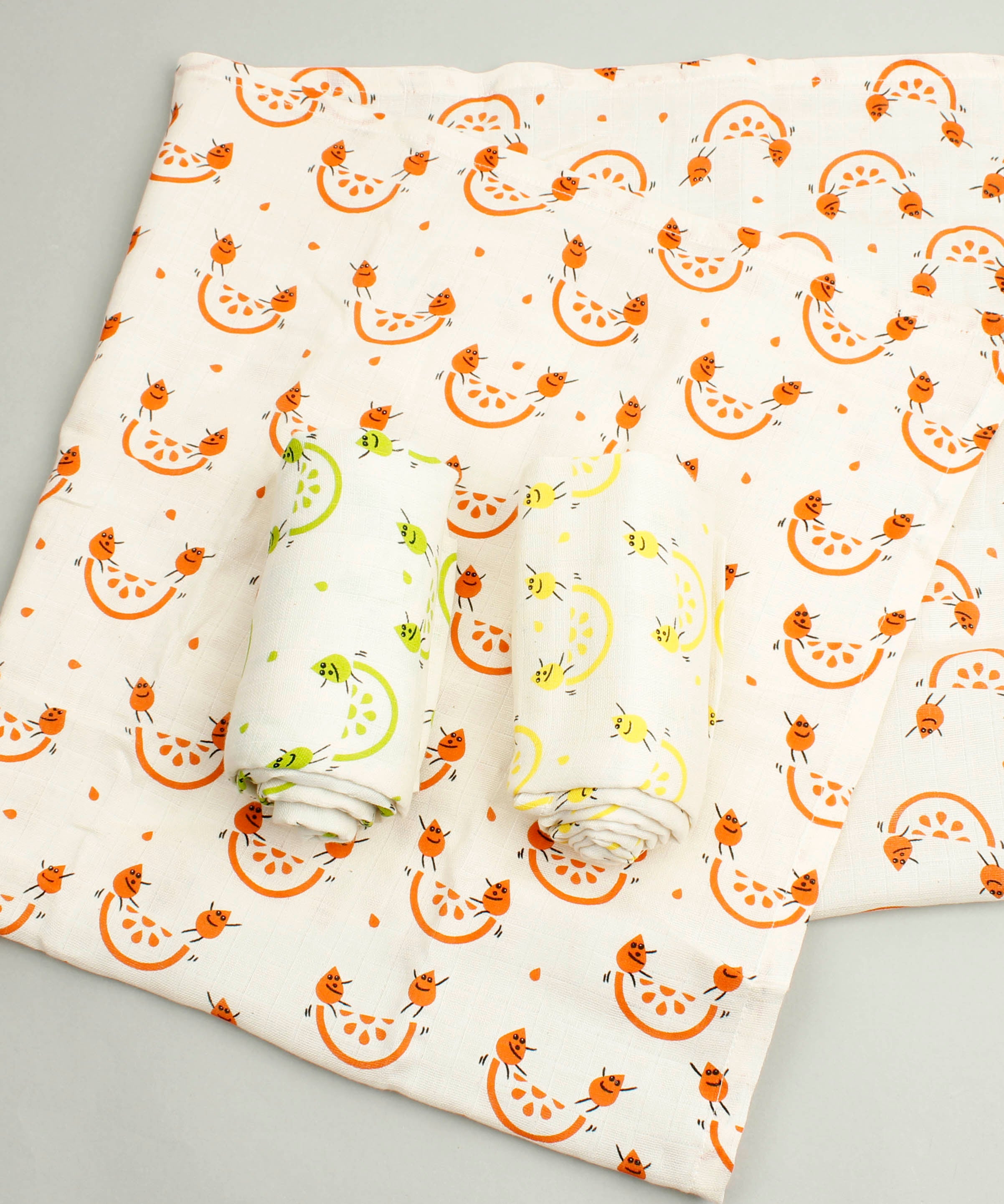 A Slice Of Green set of 3 rainbow organic cotton muslin cloths showing the orange design cloth laid flat with the lime and lemon cloth on top.