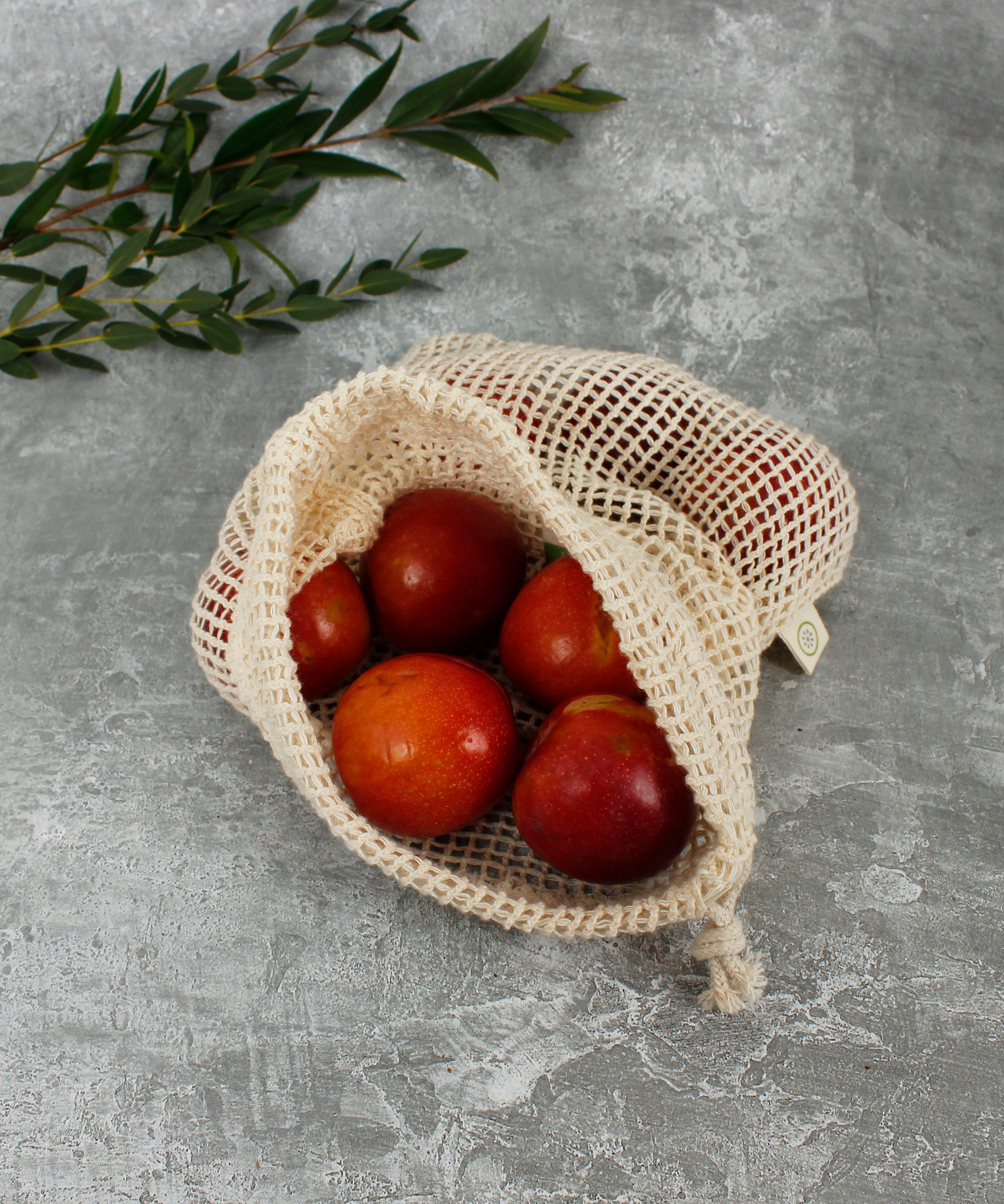 A Slice Of Green small mesh produce bag made from recycled cotton showing an opened bag with a bunch of red apples inside showing scale