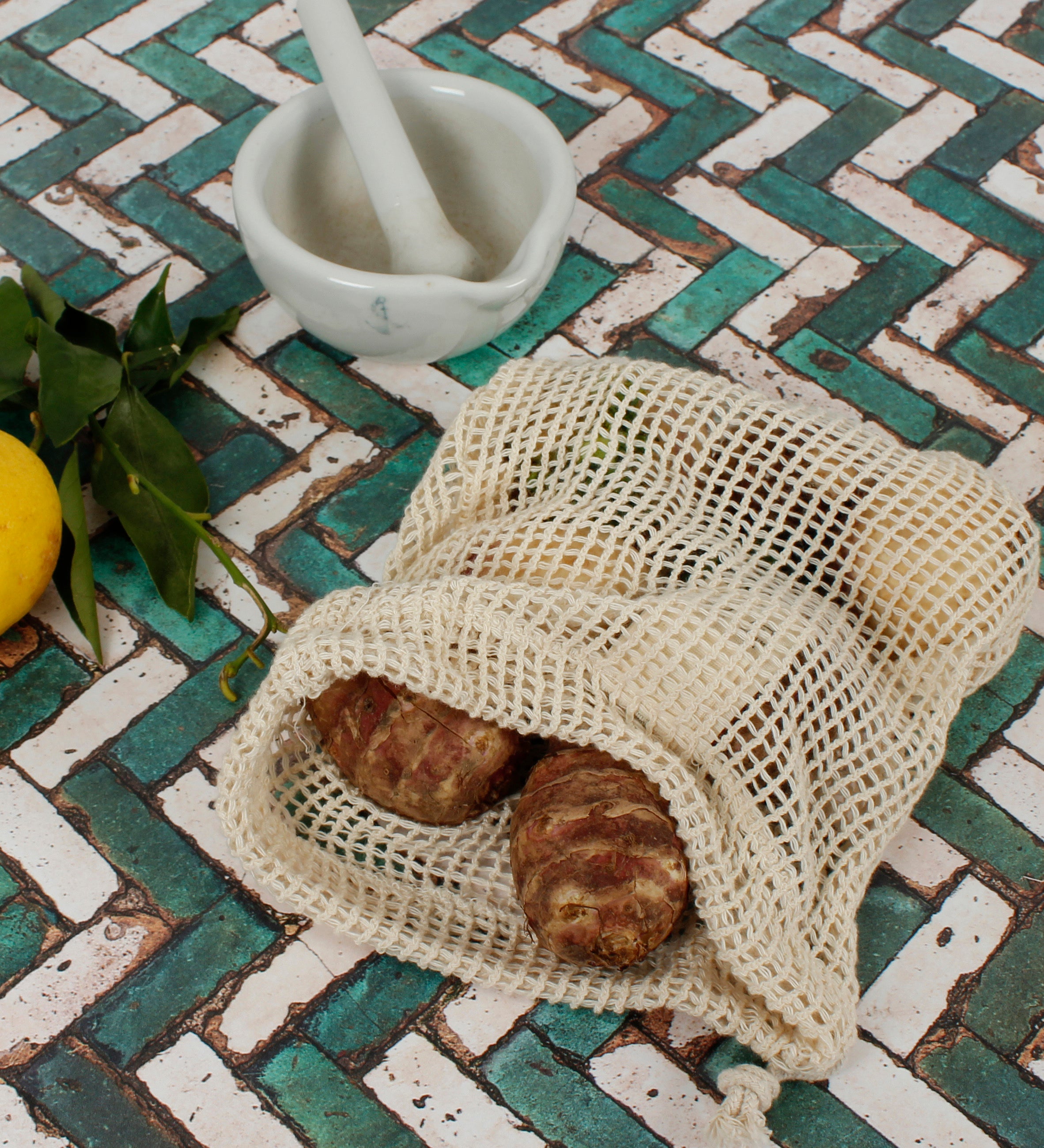 A Slice Of Green small mesh produce bag made from recycled cotton showing a opened bag with a bunch of food items inside.