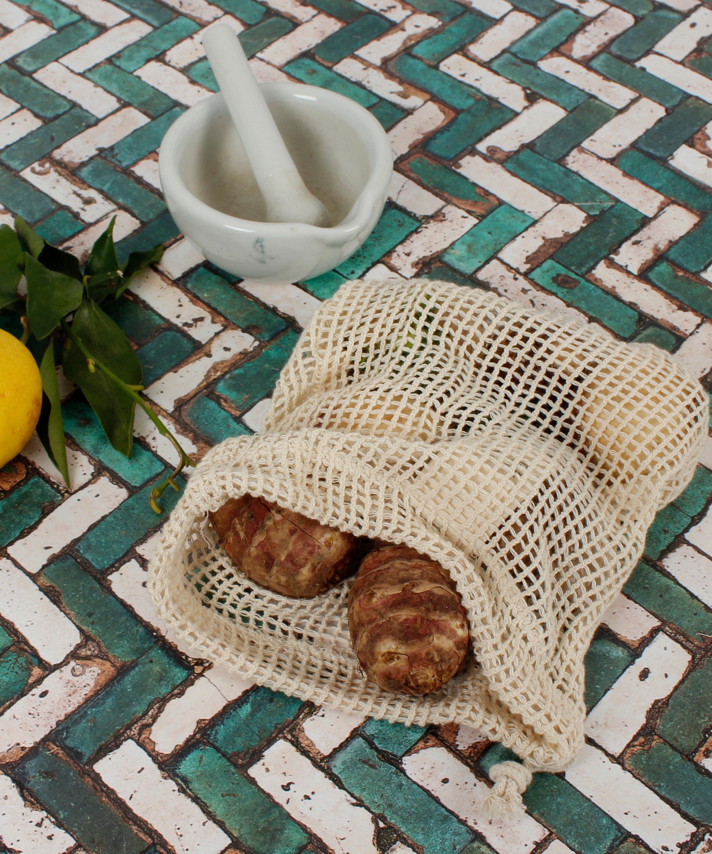 A Slice Of Green small mesh produce bag made from recycled cotton showing a opened bag with a bunch of food items inside.