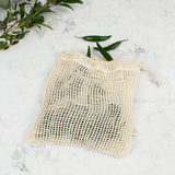 A Slice Of Green small mesh produce bag laid flat on a stone surface. A recycled cotton bag showing a bunch of green chillies inside.