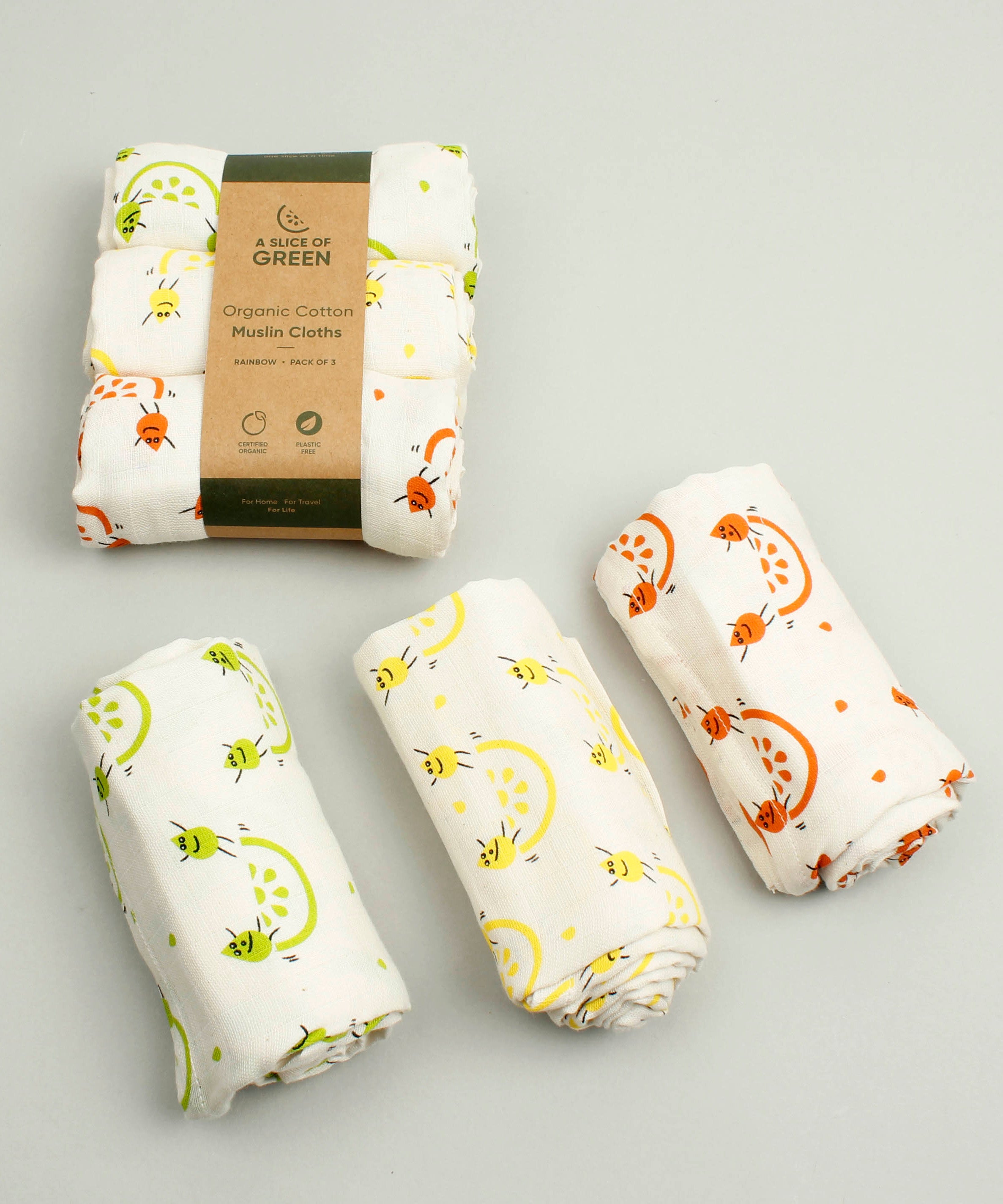 A Slice Of Green rainbow muslin cloth set rolled up and showing the fruit print detail on organic cotton fabric.