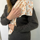 An adult with the organic cotton A Slice Of Green muslin cloth in orange design over the shoulder showing the scale of the cloth