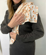 An adult with the organic cotton A Slice Of Green muslin cloth in orange design over the shoulder showing the scale of the cloth