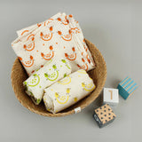 A close up of the A Slice Of Green rainbow muslin cloth set in a Respiin bowl next to 3 wooden coloured blocks