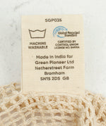 A close up view of the A Slice Of Green small mesh recycled cotton produce bag showing the certifications tag