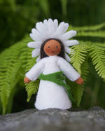 Close up of the Ambrosius oxeye daisy crown fairy doll on a rock in front of a green plant background
