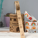 Two stacks of paper tape on a worktop. The tape on the top of the left stack has been pulled to reveal a bee design.