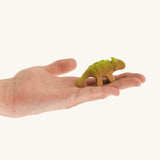 Green and light brown baby standing Akylosaurus on a hand
