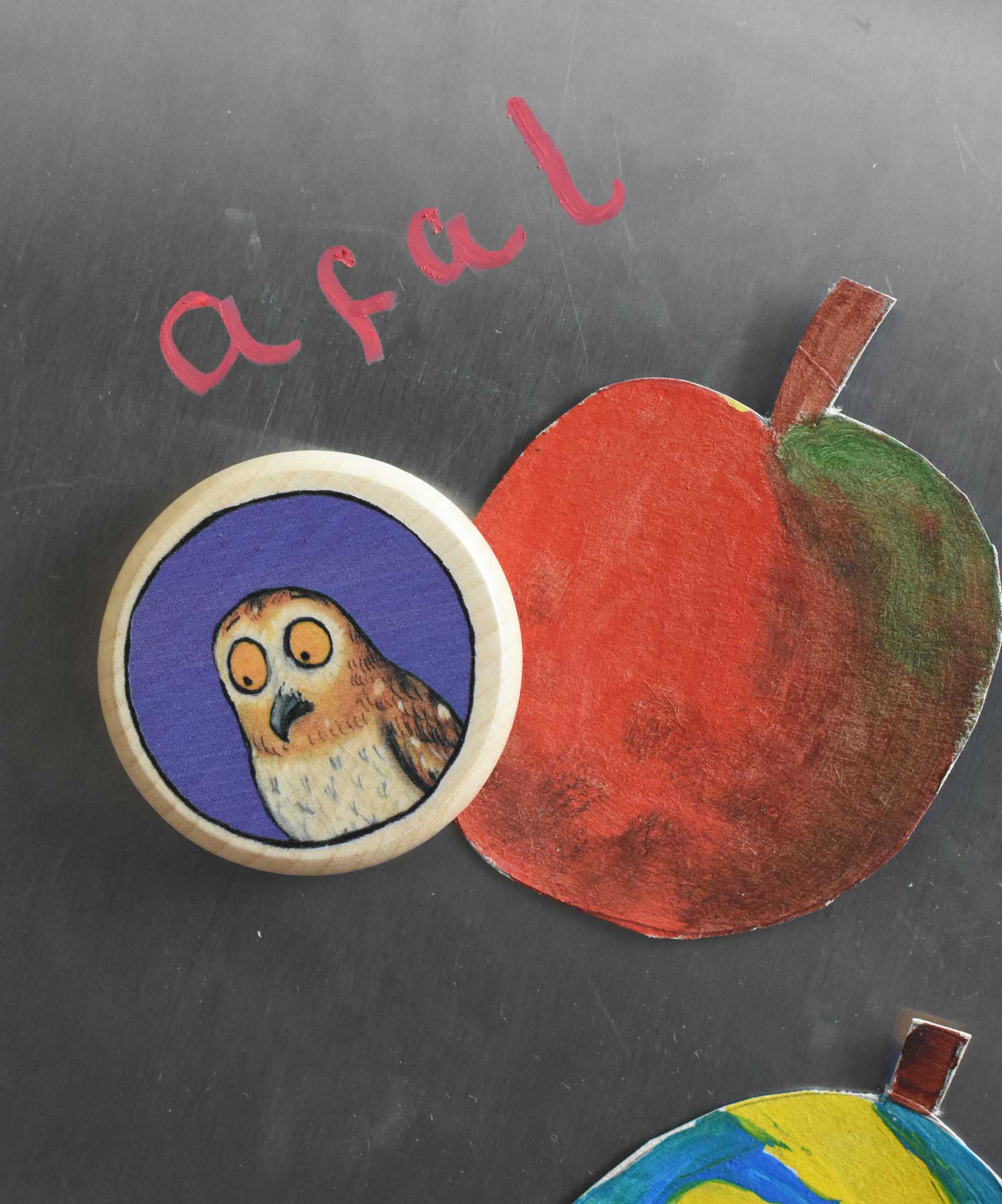 A close up of a Bajo gruffalo owl magnet stuck onto a Triclimb biri board. These magnets are part of a range of Bajo wooden toys available at Babipur.