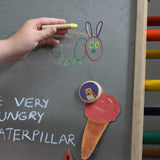A child's hand drawing on a Triclimb biri board. A hand drawnice cream placed on the Triclimb Biri board with an owl Bajo magnet. These magnets are part of a range of Bajo wooden toys available at Babipur.